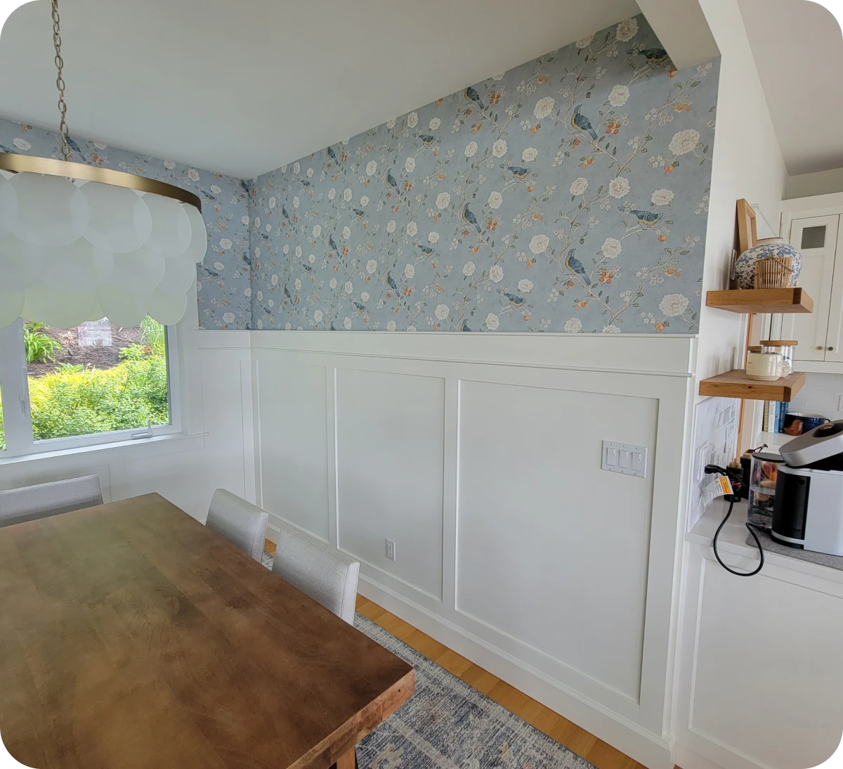Dining area with floral wallpaper and window.