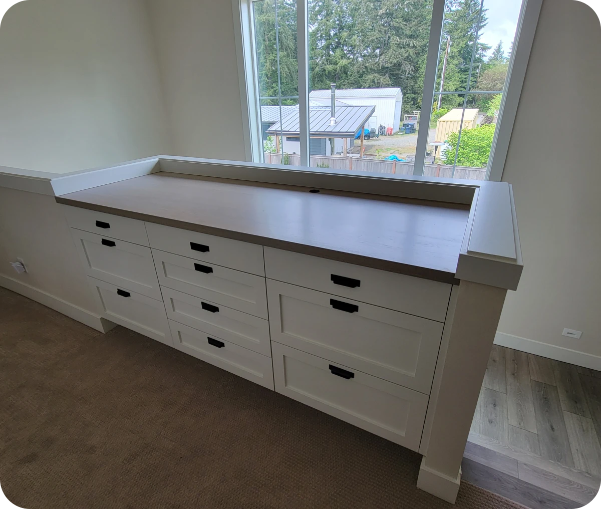 White dresser with multiple drawers under window.