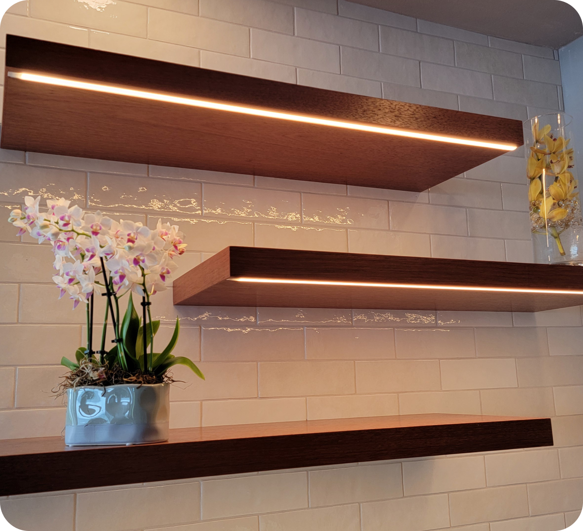Floating shelves with flowers on white tiles.